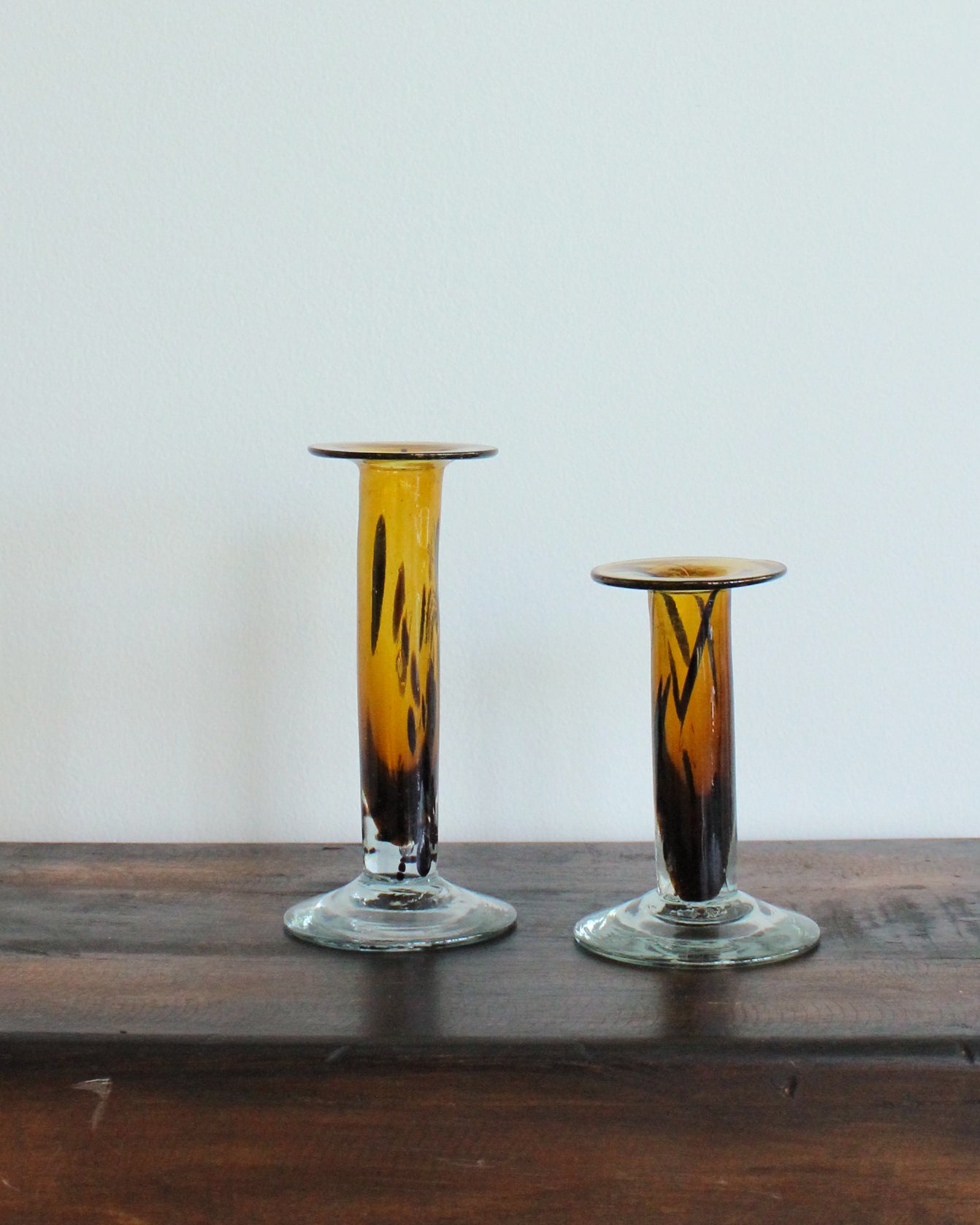 Two glass candle holders with a gradient design on a wooden surface.