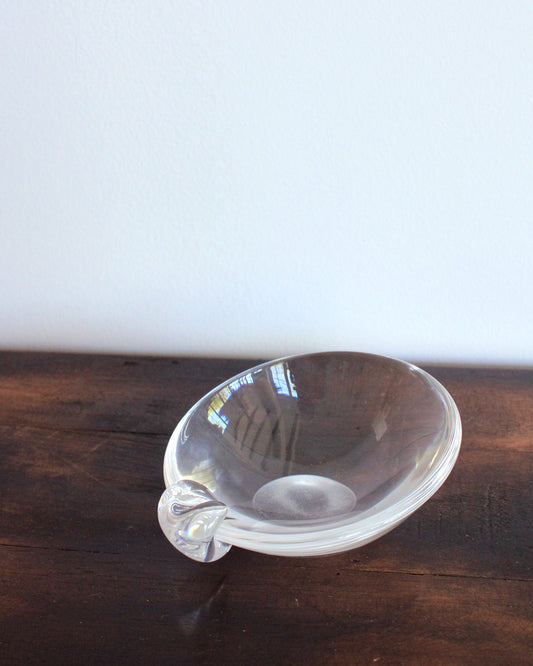 Clear glass bowl with handle on a wooden surface