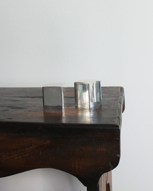 Two Chrome Salt & Pepper Shakers on a wooden surface with a plain background
