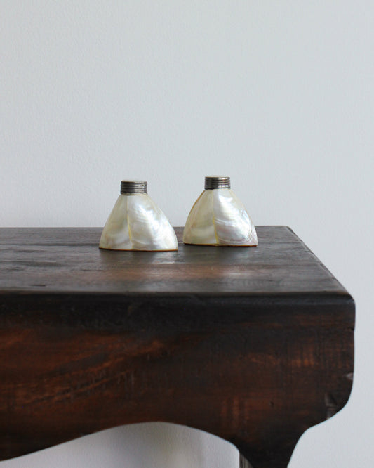 Mother of Pearl salt and pepper shakers on a wood table plain background 