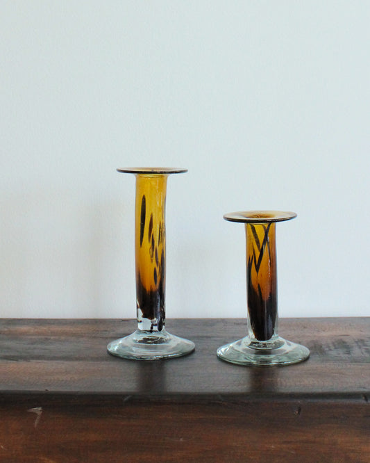 Two glass candle holders with a gradient design on a wooden surface.